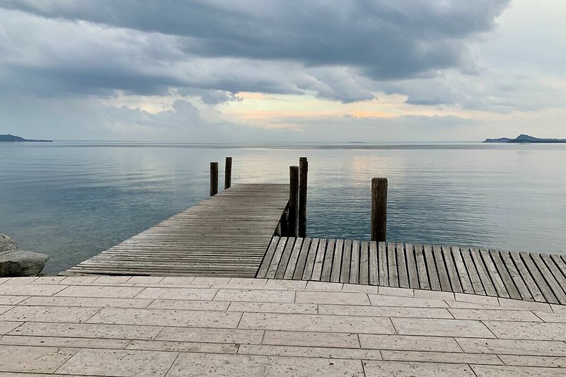 Abendstimmung am ruhigen See mit Holzsteg an der Promenade von Maderno