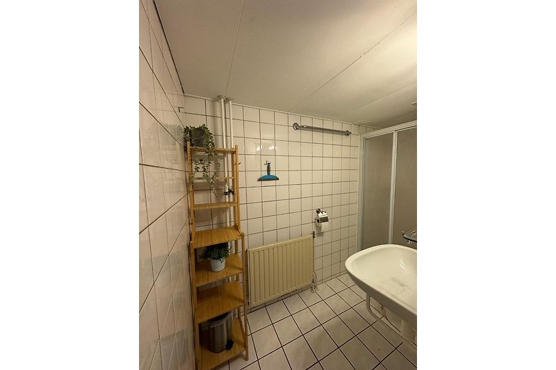 Badezimmer mit Holzregalen, Fliesen und Armaturen.