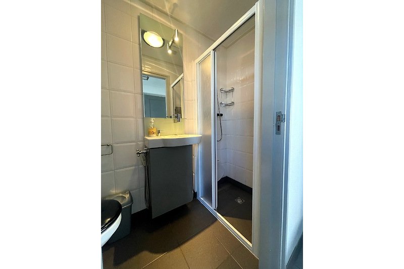 Moderne badkamer met schuifdeur, wastafel en douche.