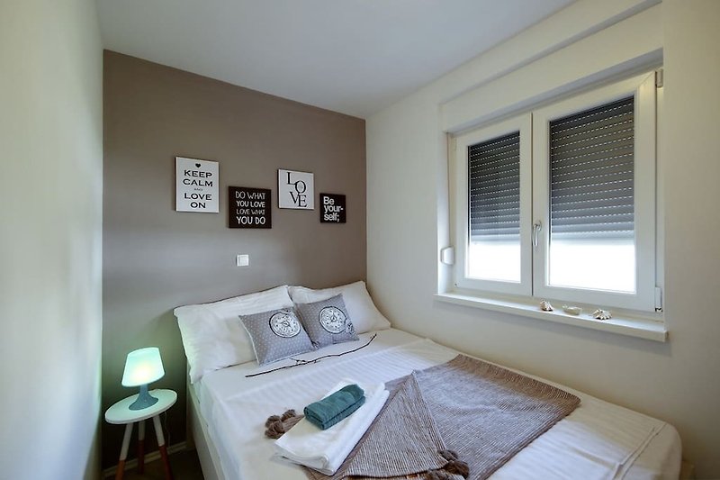 Udobna spavaća soba s udobnim namještajem i prozorom.