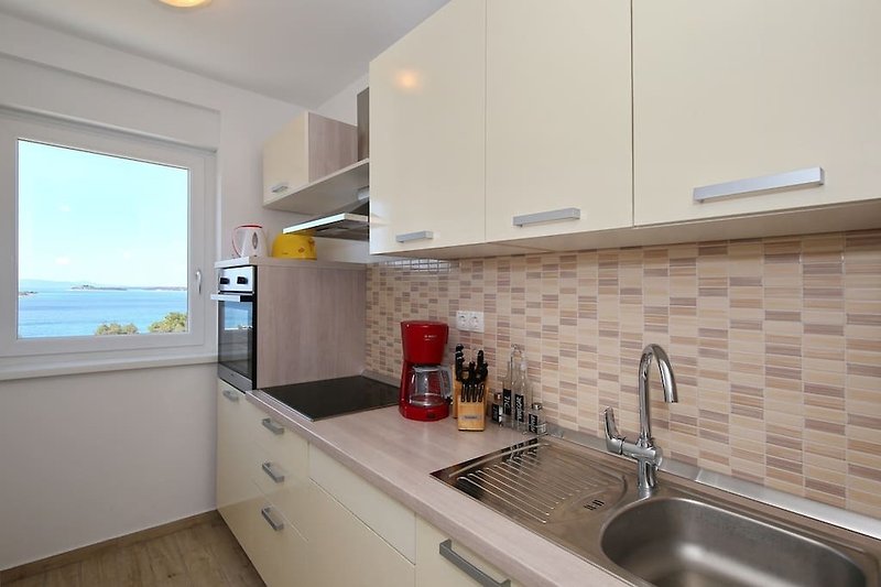 Moderni kuhinjski prostor s elegantnim ormarićima i drvenim radnim pločama. Uživajte u kuhanju u ovom dobro osmišljenom prostoru.