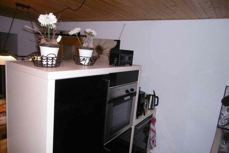 Küche mit Holzmöbeln, Blumen und moderner Ausstattung.