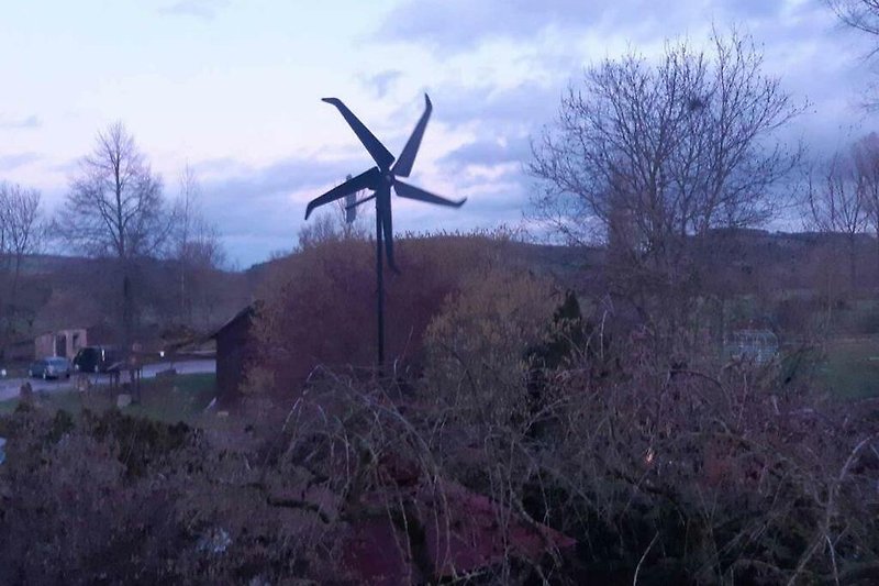 Windmühle auf grüner Wiese im Abendlicht.