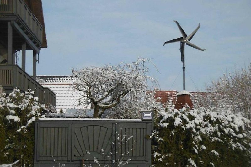 Winterlandschaft mit Haus, Schnee und Windmühle.