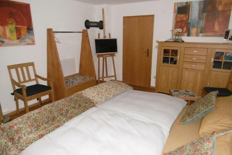 Schlafzimmer mit gemütlichem Bett, Nachttisch und Fenster.