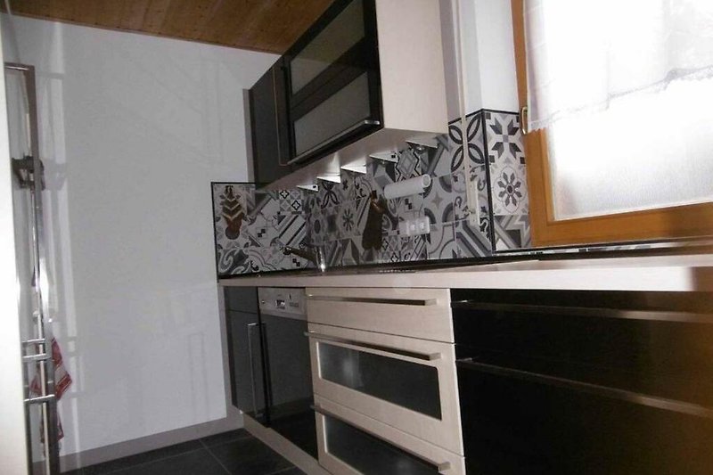 Moderne Küche mit grauen Schränken, Holztheke und Küchengeräten.