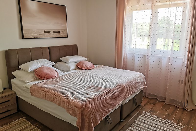 Elegantna spavaća soba s udobnim krevetom i lijepim drvenim namještajem.