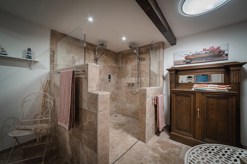 Elegantes Badezimmer mit Dusche, Holzmöbeln und Kunst.