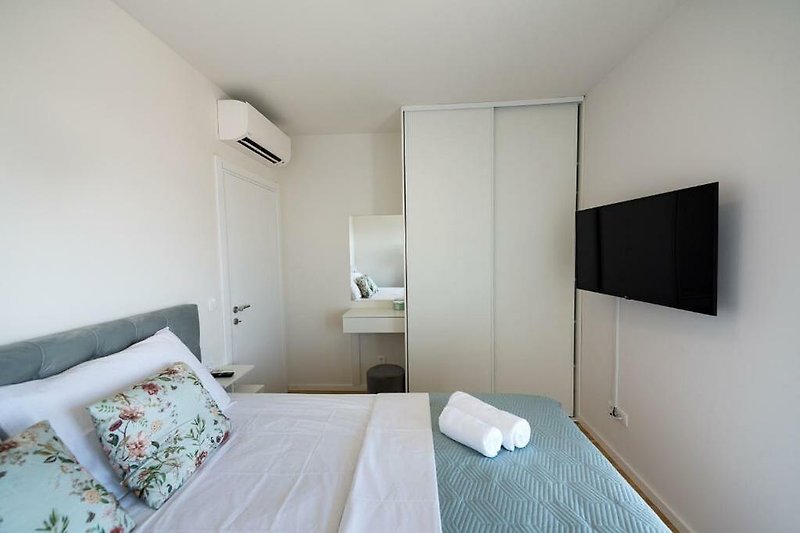 Modernes Schlafzimmer mit Klimaanlage, TV und Balkon.