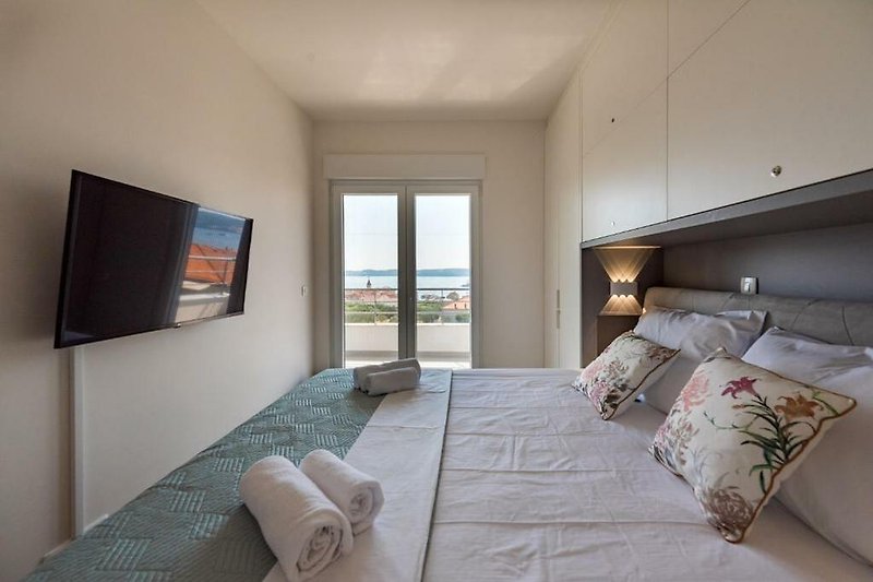 Modernes Schlafzimmer mit Klimaanlage, TV und Balkon.