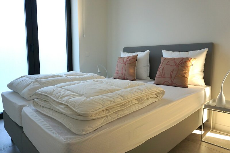 Modernes Schlafzimmer mit bequemem Bett, Holzmöbeln und stilvoller Lampe.