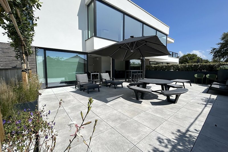 Schöne Terrasse mit Tisch und Pflanzen, Blick auf Garten und Haus.
