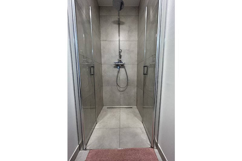 Elegantes Badezimmer mit Dusche, Glaswand und Metallarmaturen.