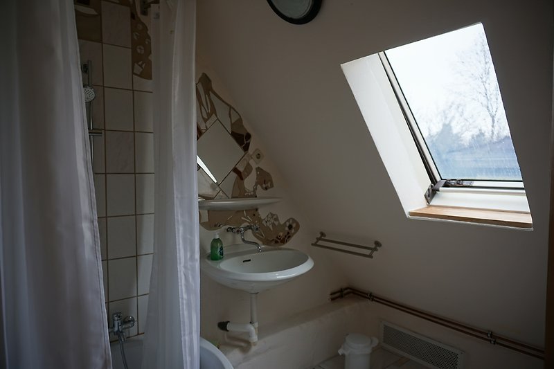 Badezimmer mit Fenster, Toilette und Waschbecken.