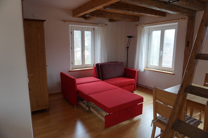Wohnzimmer mit bequemer Couch, Tisch und Fenster.