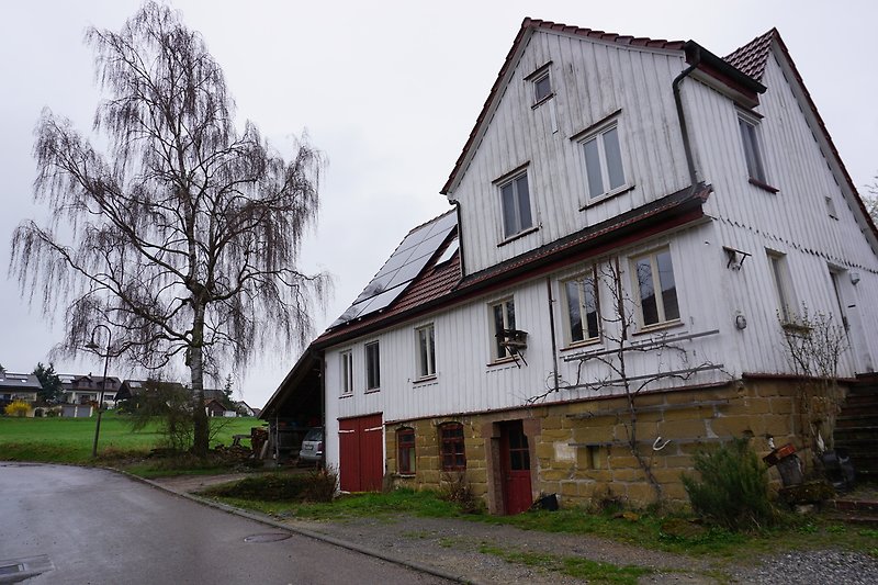 Historisches Haus mit Fachwerk, Fenstern und Dach in ländlicher Umgebung.