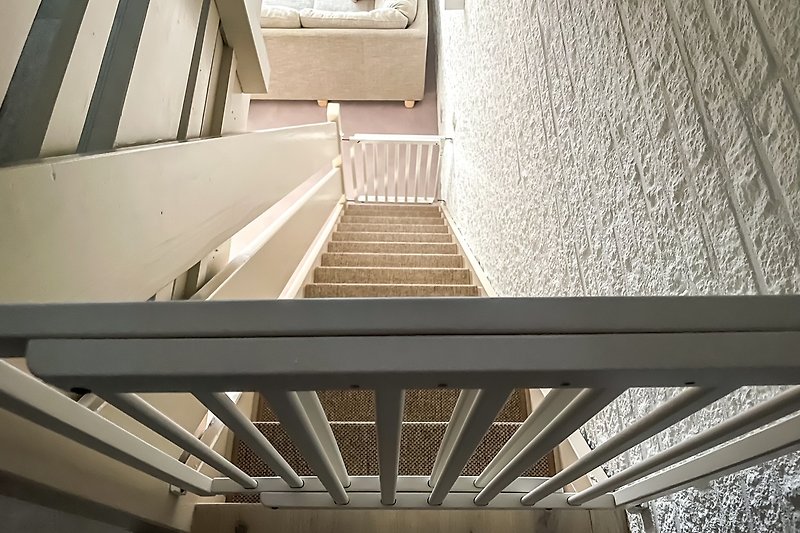 De trap heeft boven en beneden een traphekje.