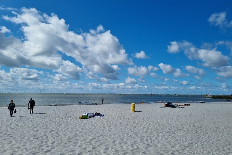 Strandurlaub mit blauem Himmel, türkisem Wasser und entspannten Menschen.
