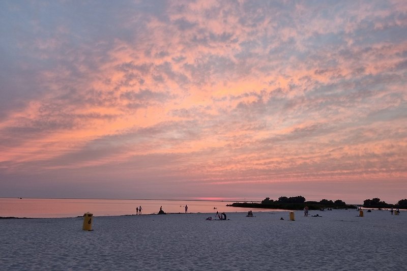Traumhafter Sonnenuntergang am Strand mit rotem Himmel.