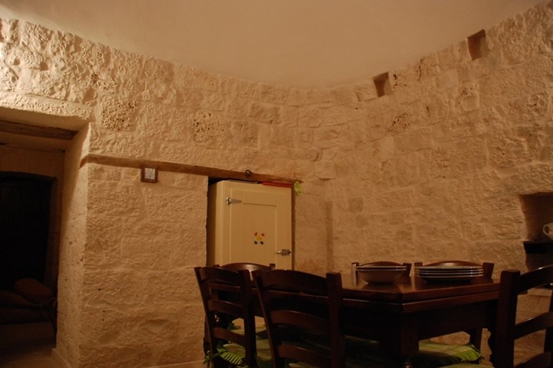 Historisches Zimmer mit Holzdecke, antikem Mauerwerk und Holztisch.