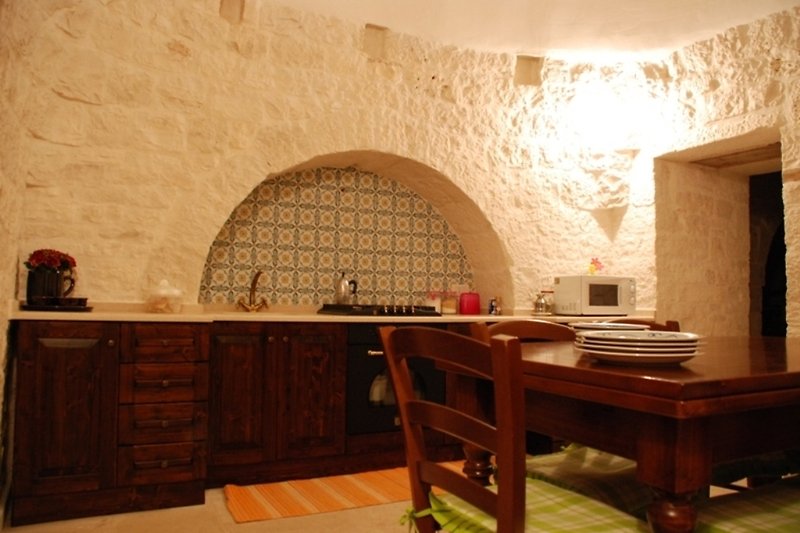 Küche mit Holzschrank, Tisch und Ziegelwand.