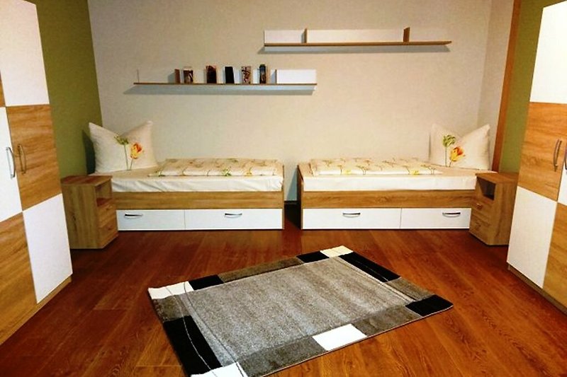 Schlafzimmer 2 mit zwei Kleiderschränken,Holzbetten und stilvollem Dekor.