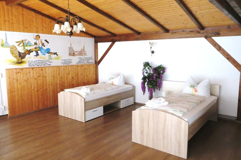 Schlafzimmer 3 mit 2 auseinanderstehenden Betten, ein Kleiderschrank, Tisch und Stühle, dekorativer Wandgestaltung.