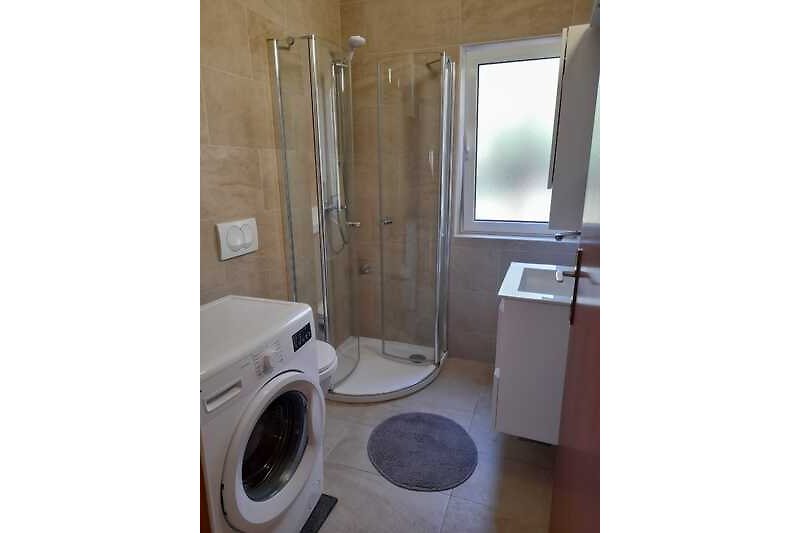 Modernes Badezimmer mit Waschmaschine und Fenster.