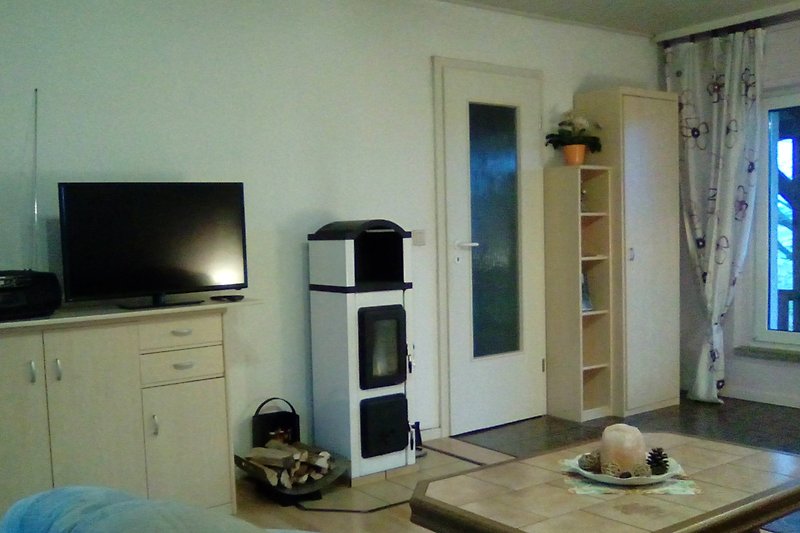 Wohnzimmer mit Radio, Fernseher und Kaminofen