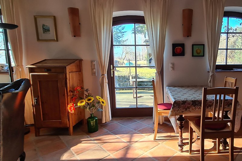 Wohnzimmer mit Holzmöbeln, Pflanzen und Fensterblick. Gemütliche Einrichtung.