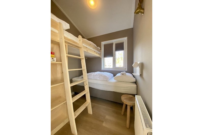 Schlafzimmer mit gemütlichem Bett, Holzmöbeln und Fensterblick.