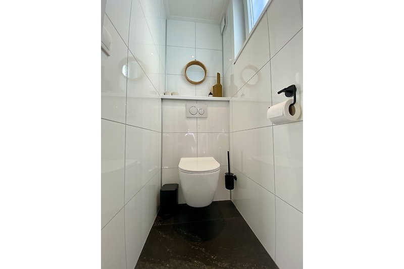 Modernes Badezimmer mit Toilette, Waschbecken und Armatur.
