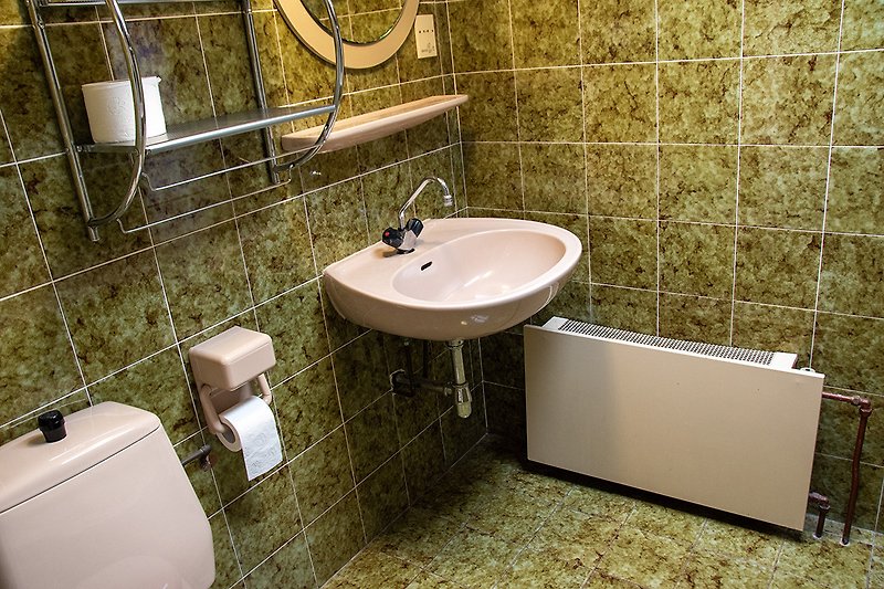 Badezimmer mit Waschbecken, Pflanze und Marmorbadewanne.