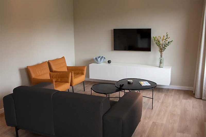 Wohnzimmer mit Holzmöbeln, Fernseher, Pflanze und Tisch.