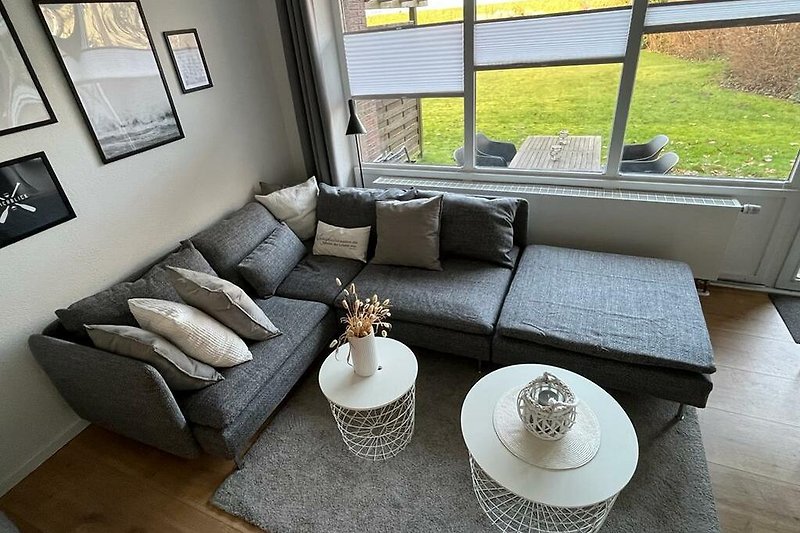 Wohnzimmer mit gemütlicher Couch, stilvollem Tisch, Pflanzen und Lampen.