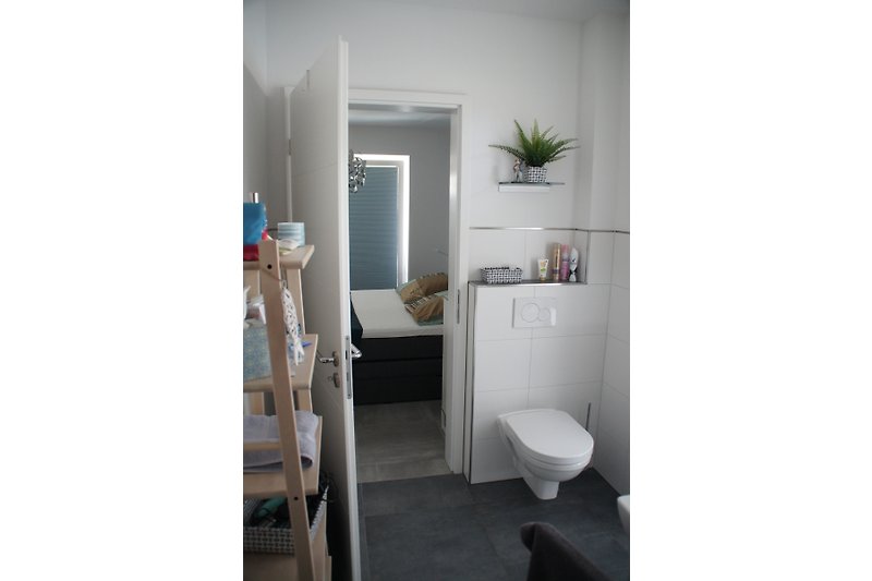 Badezimmer mit Holzregal und Tür zum Schlafzimmer