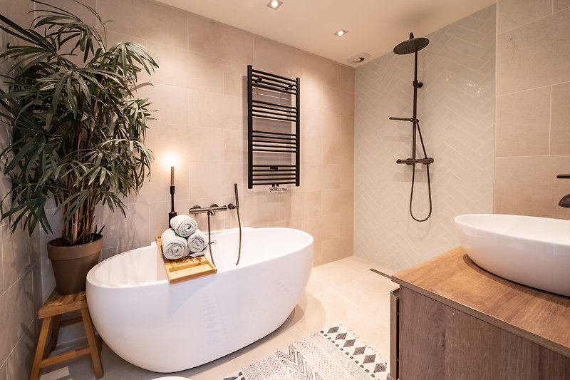 Modernes Badezimmer mit Pflanzen, Badewanne und Armaturen.