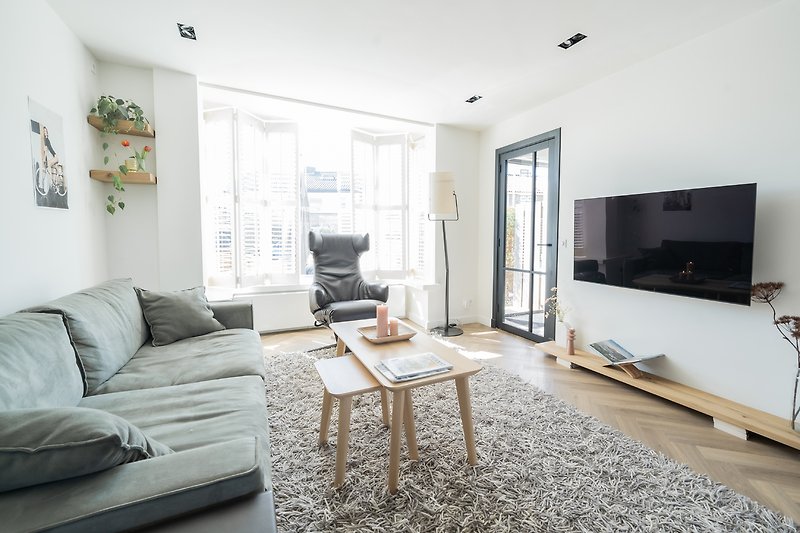 Modernes Wohnzimmer mit bequemer Couch, Holztisch, Fernseher und stilvoller Einrichtung.