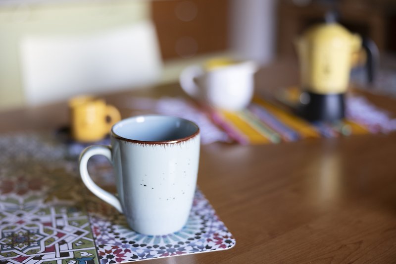 Tasse, Teller, Kaffeetasse auf Tisch mit Tischdecke.