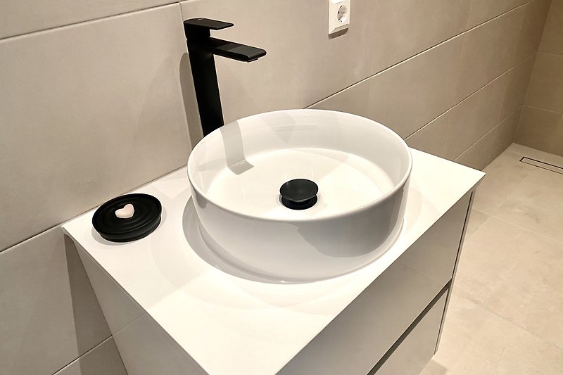 De moderne badkamer is voorzien van een inloopdouche, wastafel en toilet.