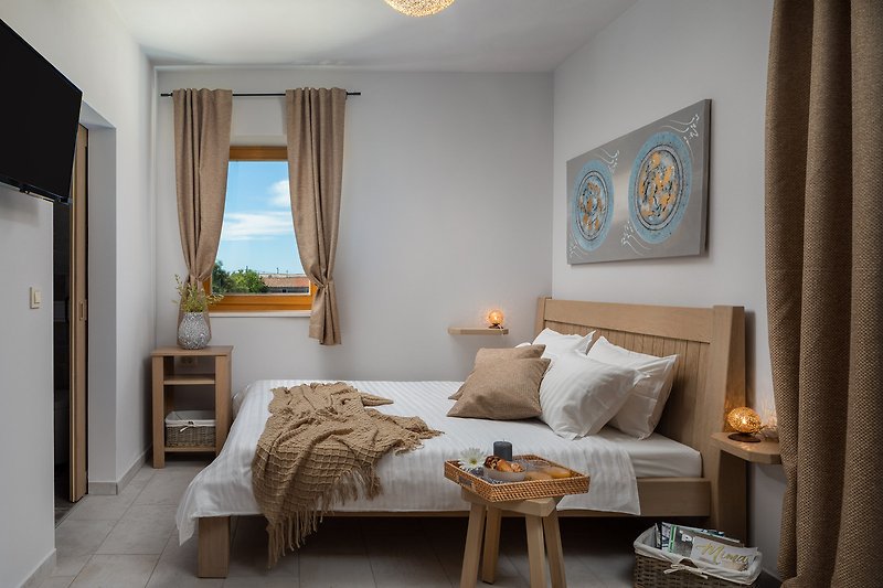 Stilvolles Schlafzimmer mit Holzmöbeln, gemütlichem Bett und Fensterblick.