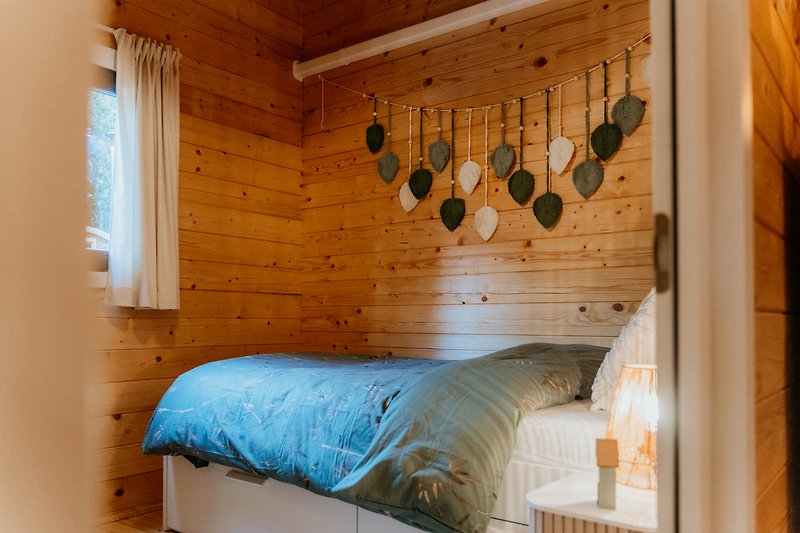Rustikales Schlafzimmer mit Holzbalken, Bett und Vorhängen. Gemütliche Atmosphäre.