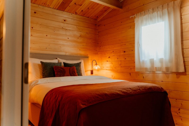 Gemütliches Schlafzimmer mit Holzmöbeln, Bett und Lampen. Gemütliche Atmosphäre.
