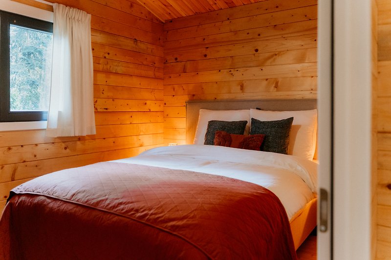 Rustikales Schlafzimmer mit gemütlichem Bett und Lampenschirm. Gemütliche Atmosphäre.