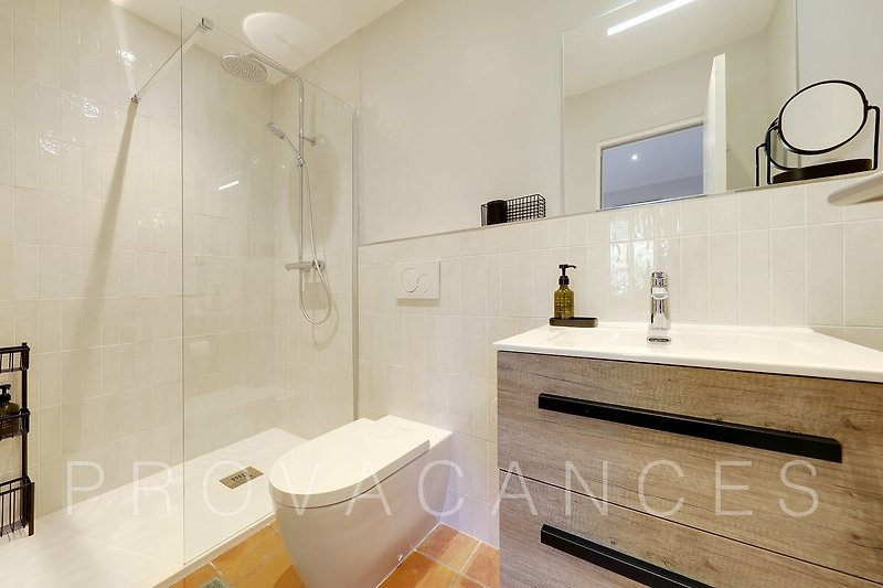 Badezimmer mit Holzschrank, Spiegel und Dusche.