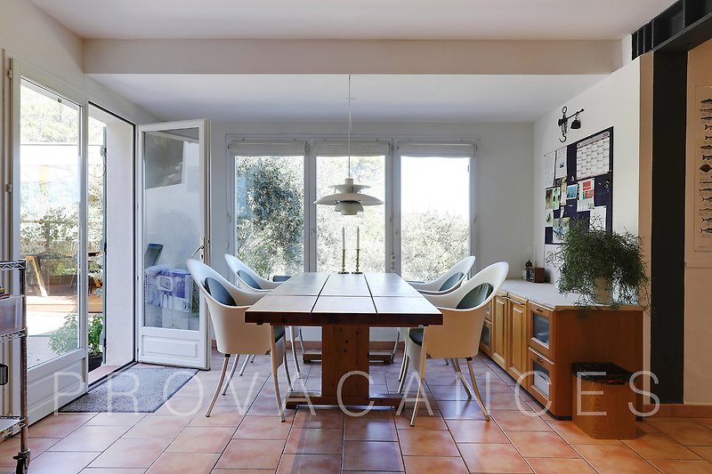 Wohnzimmer mit Tisch, Stühlen, Fenster und Pflanze. Gemütliche Einrichtung.