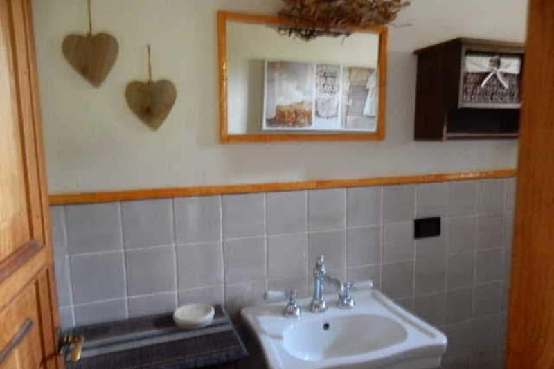 Badezimmer mit braunem Waschbecken, Spiegel und Fenster.