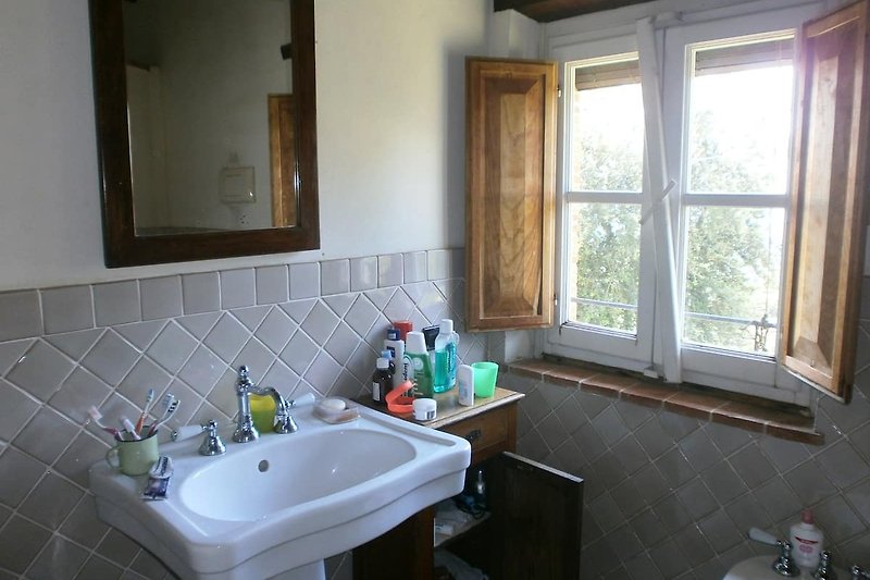 Modernes Badezimmer mit Spiegel, Waschbecken und Fenster.