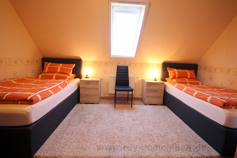Schlafzimmer mit gemütlichem Bett, Holzmöbeln und Fenster.