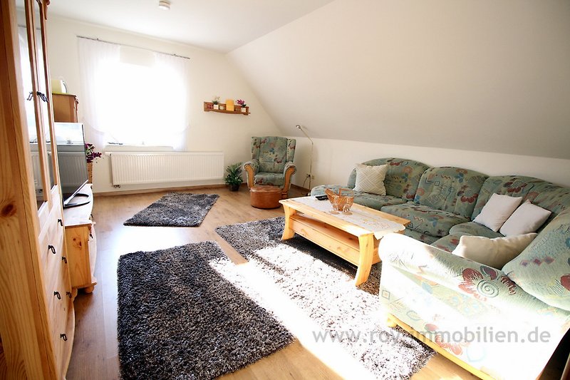 Wohnzimmer mit Sofa, Holzboden, Lampe & Bilderrahmen.